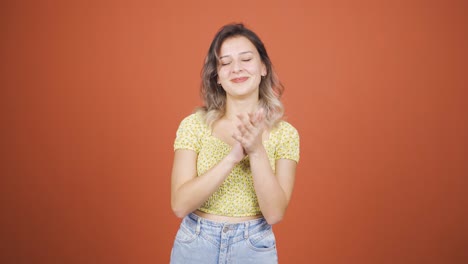 una mujer joven aplaudiendo emocionada a la cámara.