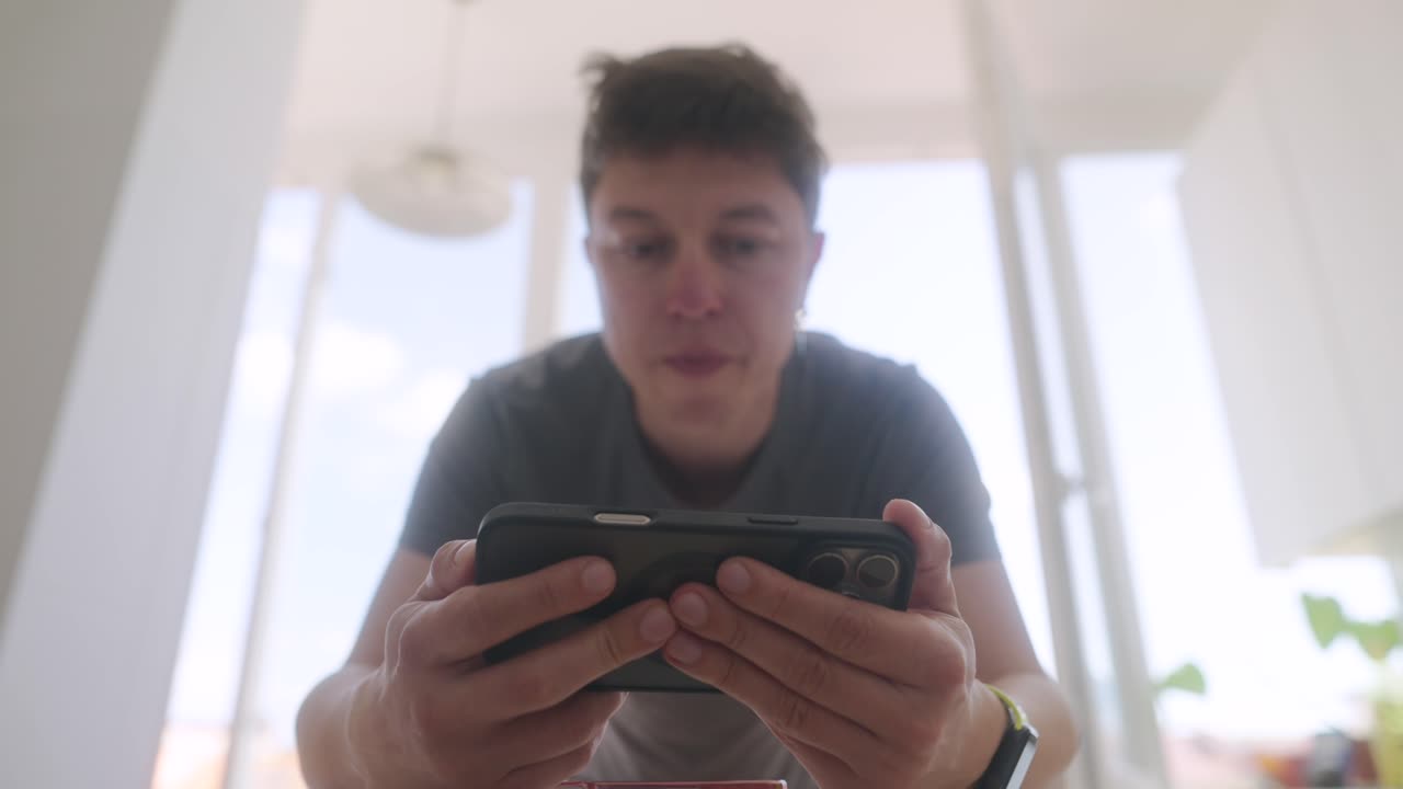 Man Playing Mobile Game in Kitchen