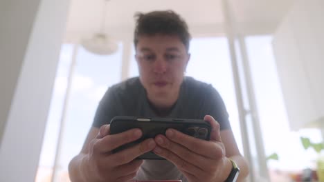 man playing mobile game in kitchen