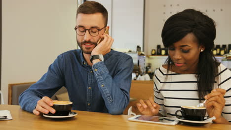 young caucasian man drinking coffee with african american woman in stylish cafe