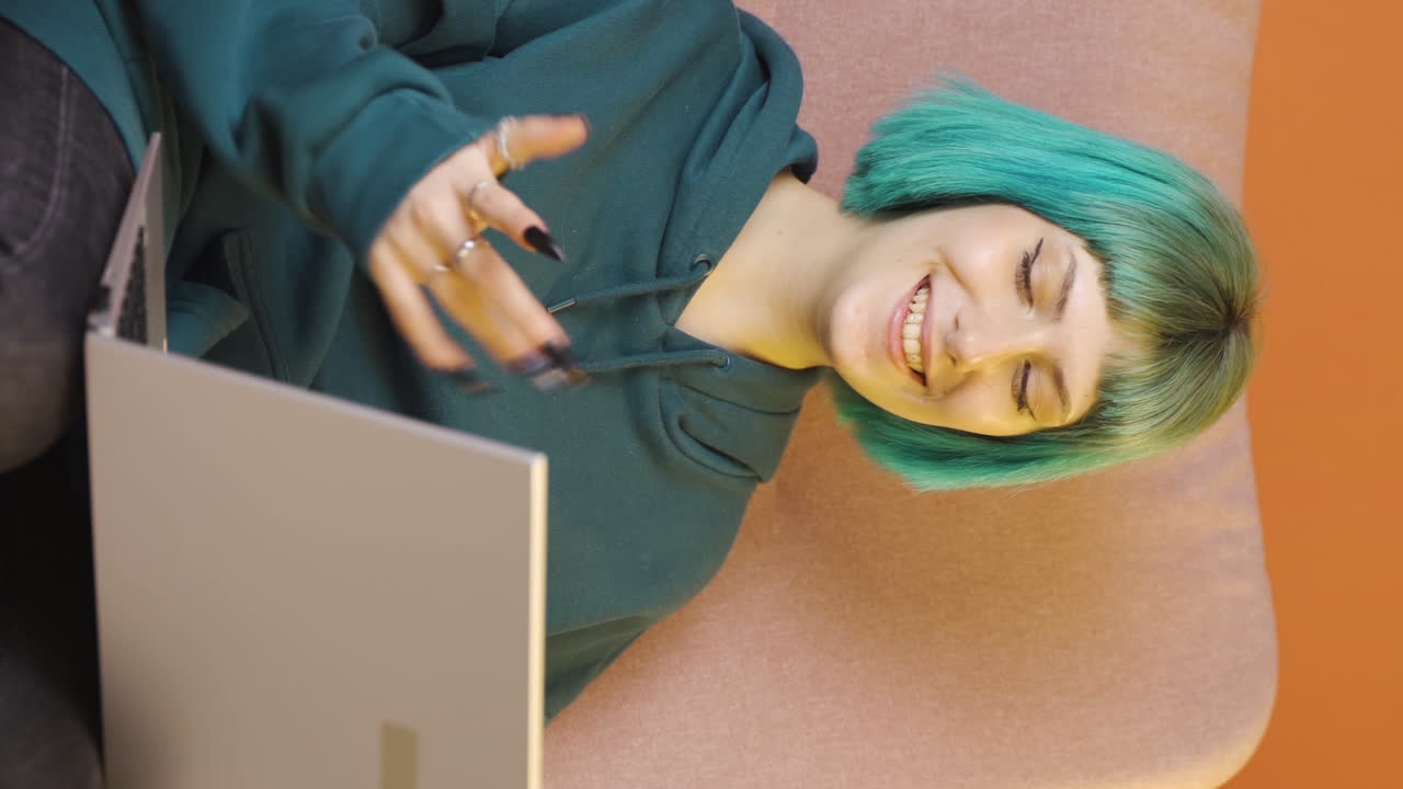 video vertical de una mujer joven mirando una computadora portátil haciendo un gesto positivo.
