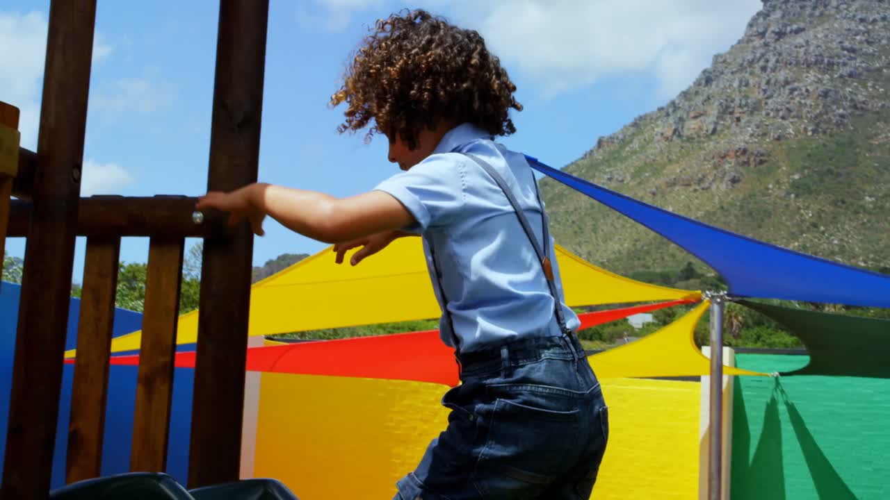 vista lateral de una escolar de raza mixta jugando en el patio de recreo de la escuela en un día soleado 4k