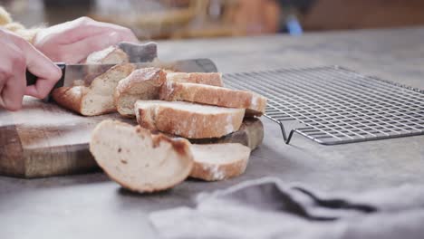 de manos de hombre caucásico cortando pan en la cocina, cámara lenta