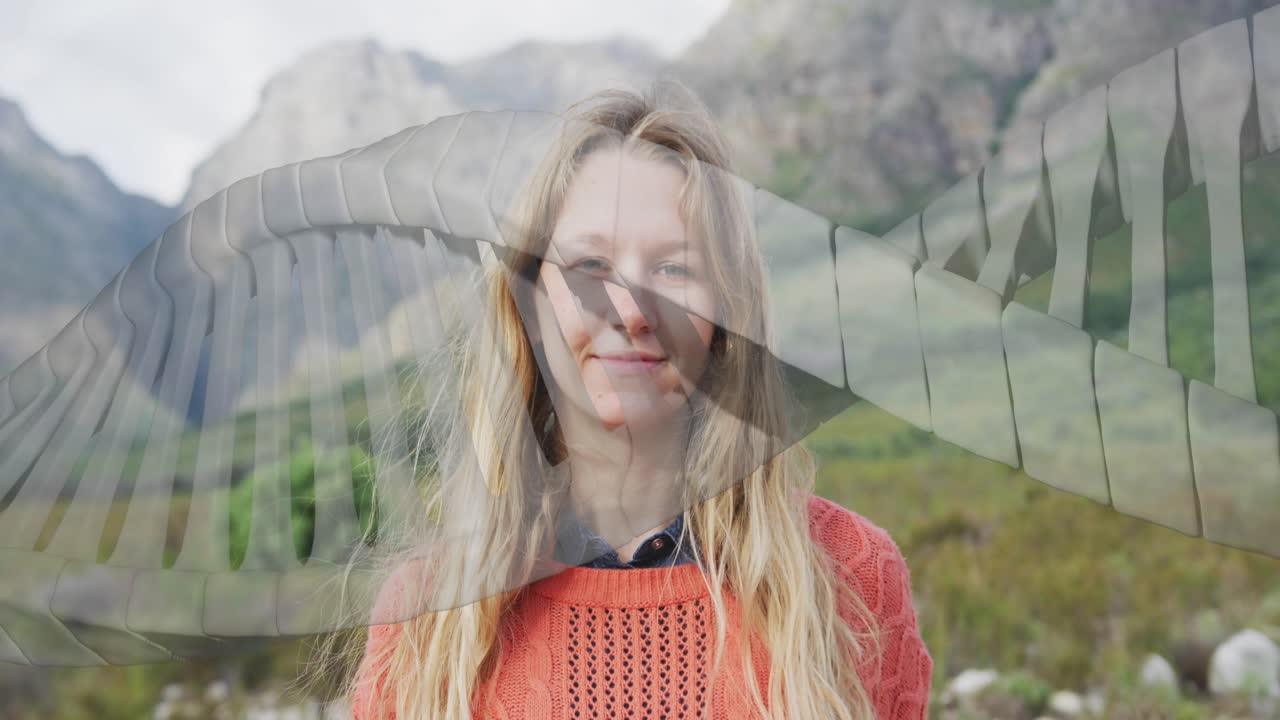 Donna in piedi davanti alle montagne, con grafica che scorre sul busto, che accenna un sorriso per la tecnologia
