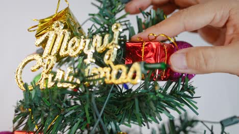 woman decorating christmas tree with baubles, lights and small gift presents for new year 2020 isolated on white background.