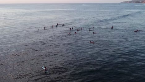 Antena-De-Un-Grupo-De-Surfistas-Esperando-Olas-En-Una-Noche-Tranquila-En-Sayulita,-México