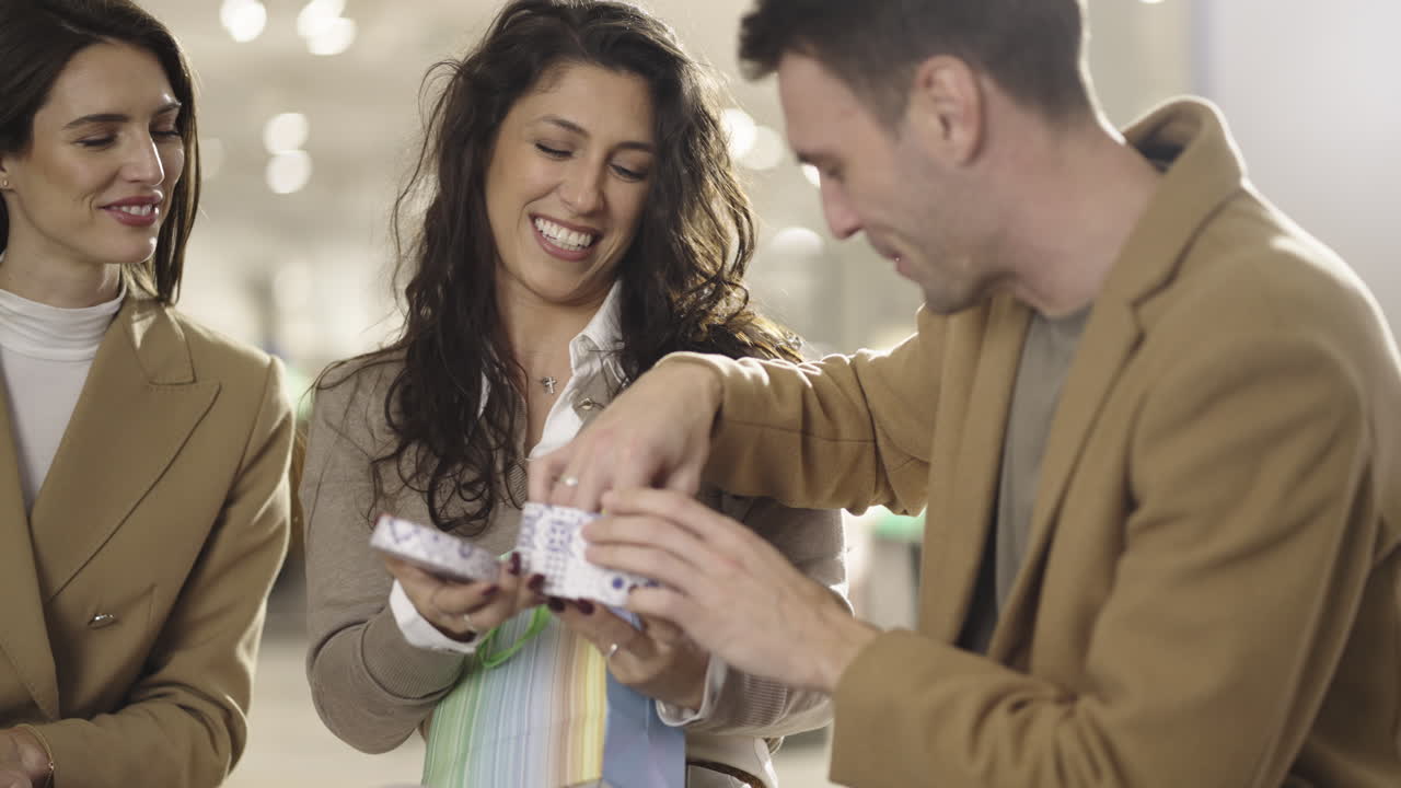Friends or a couple unboxing a gift and celebrating in a shopping mall or store