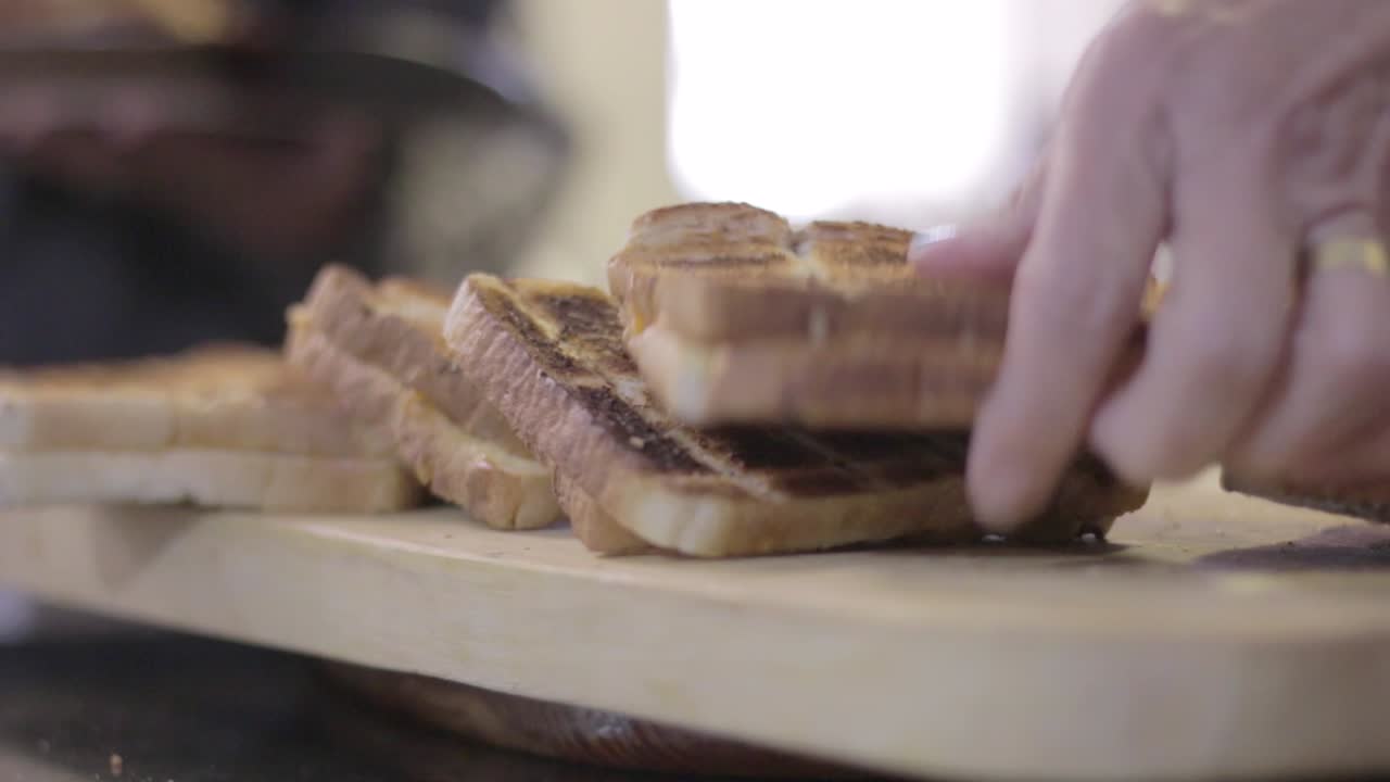 Elderley woman cutting grilled sandwiches for lunch