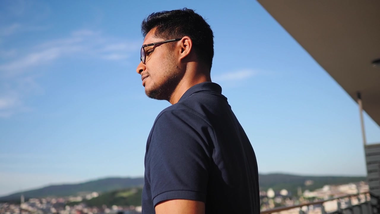 Young Man Looking at City View from Balcony