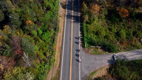 Una-Vista-Aérea-De-Gran-ángulo-Sobre-Una-Carretera-Rural-Con-árboles-Coloridos-A-Ambos-Lados-En-Un-Día-Soleado-De-Otoño