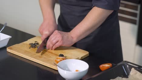 chef preparing a dish with tomatoes and olives