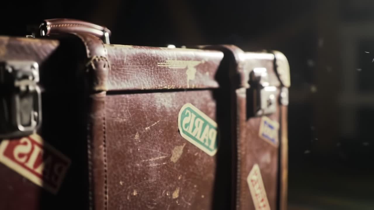 A Close-Up Journey Through Time: An Old Suitcase Capturing Memories in Dim Light, Embellished with Travel Stickers Reflecting Adventures Past