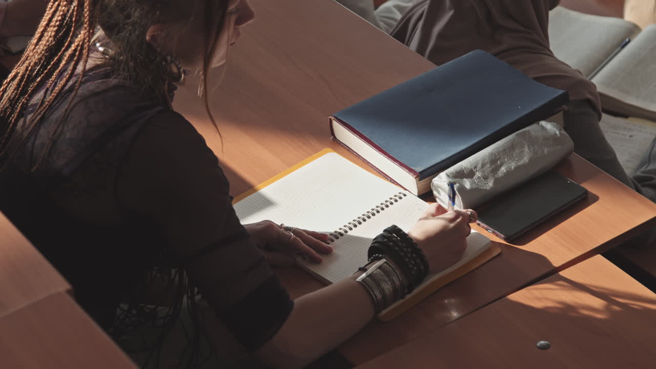 Female Student with Dreadlocks Taking Notes in Copybook