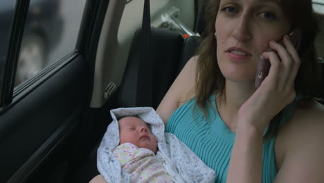 woman with baby in hands talking on phone