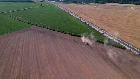 Aerial-pullback-rises-from-tractor-turning-with-smoke-cloud-behind