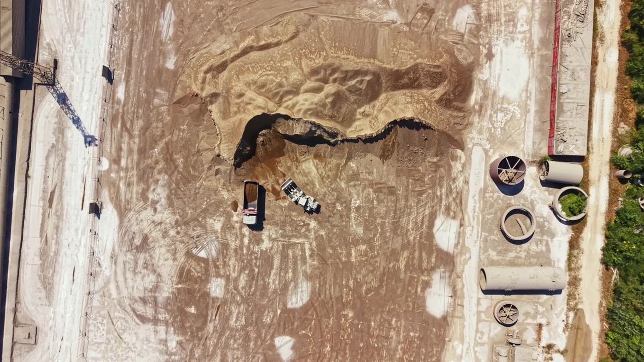Cantiere edile mostra una vasta area di terra e attrezzature durante le ore diurne.