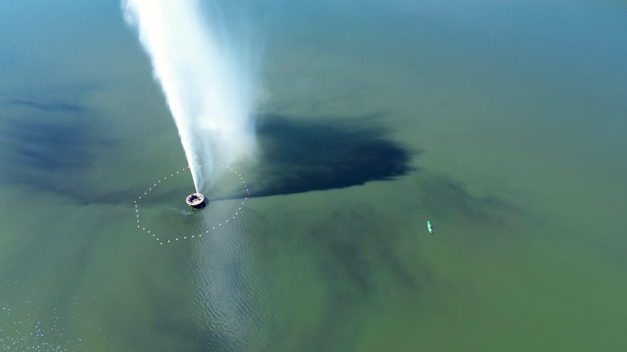 Drone aerial landscape of kayak paddling next to jets spraying water in memorial fountain in Lake Burley Griffin reservoir basin Canberra city capital ACT Australia travel tourism leisure outdoors