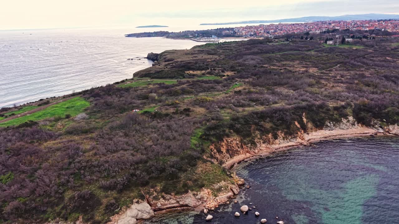 Aerial view of coastal landscape with rocky shores and green hills