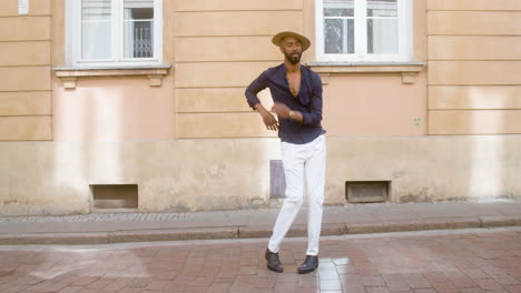 happy afro caribbean man with panama hat dancing latin choreographies alone in street 2