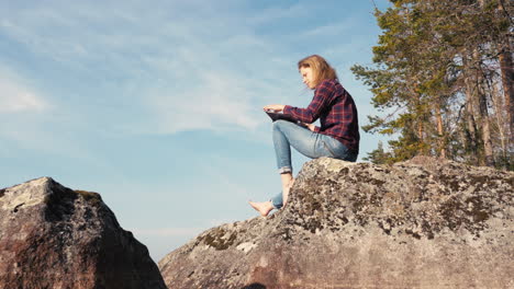 girl opening and reading the bible on a rock in the forest on a sunny day