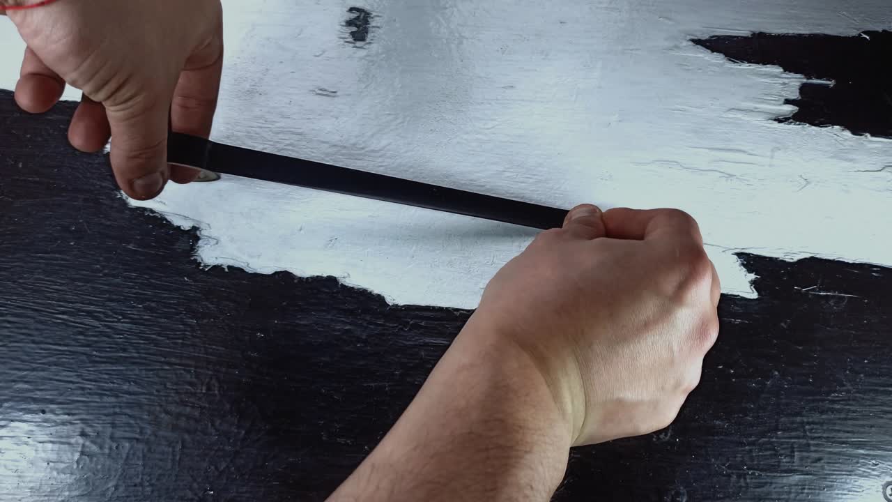 남자는 나무 테이블에 검은 테이프를 붙인다.