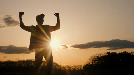 silhouette of a man celebrating at sunset