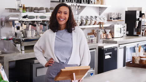 Dueño-De-La-Cafetería-Femenina-De-Raza-Mixta-Sonriendo-Detrás-Del-Mostrador