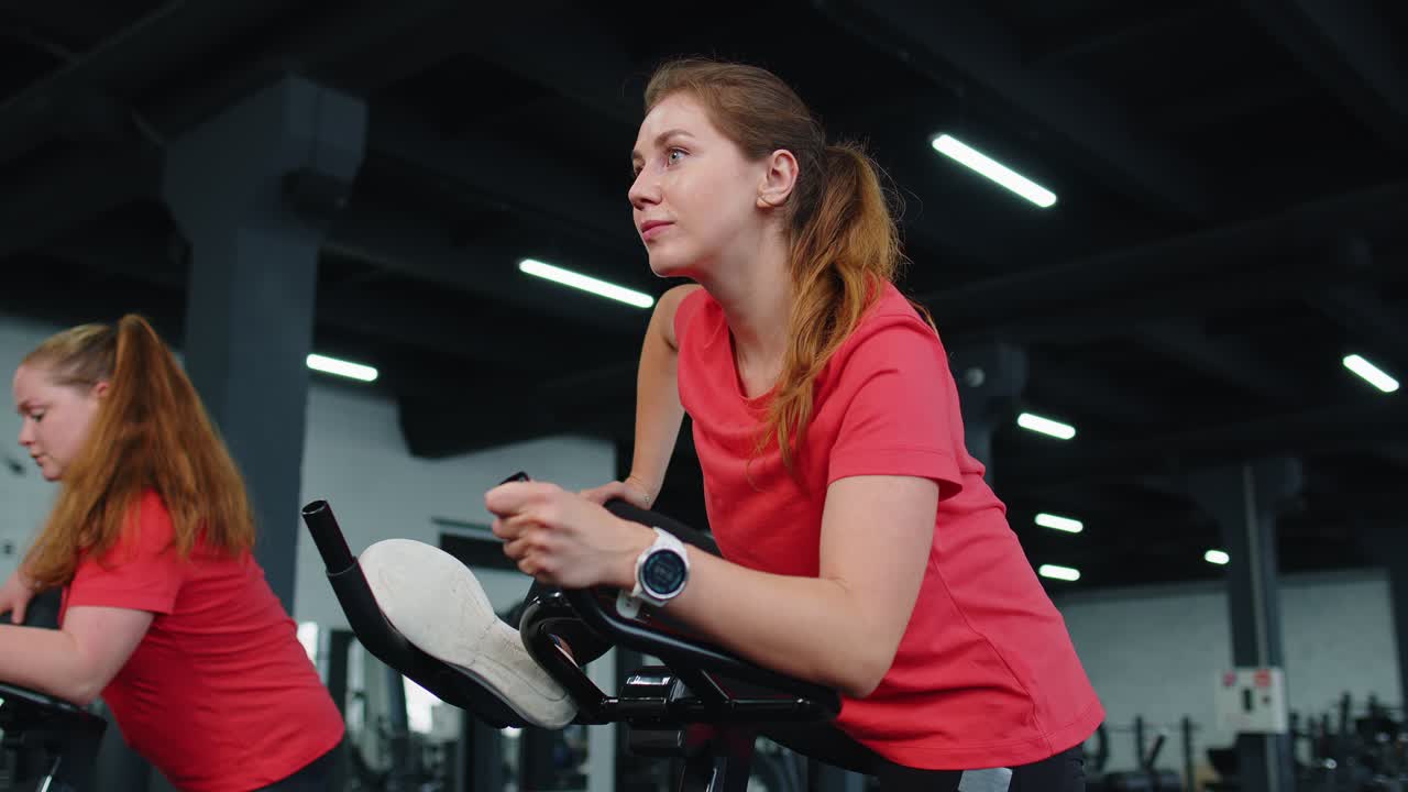 Gruppo di ragazze che esegue un allenamento di stretching, esercizi cardio su simulatori di bici per l'allenamento ciclistico