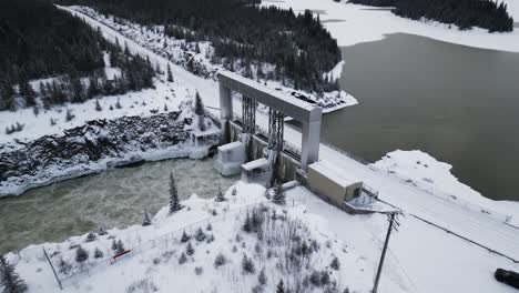 Lange-Schneebedeckte-Straße-Mit-Langsamer-Luftdrohne-Umkreist-Rauschendes-Wasser-Des-Notigi-Staudamms-In-Der-Arktis