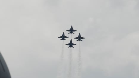 blue angels flying in formation of four together side by side at airport airshow in summer