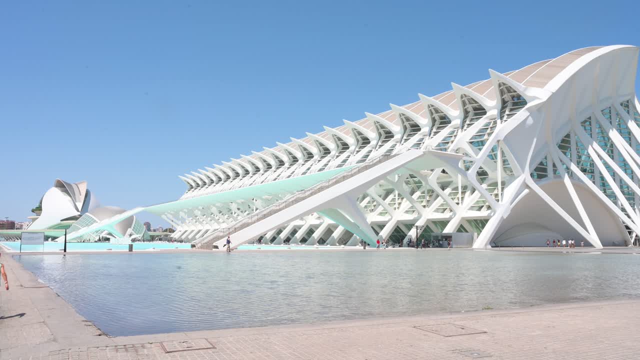 Tilt-down view of visitors walking across the frame in front of the Science Museum within the City of Arts and Sciences complex in Valencia. It is the city's most important tourist destination.