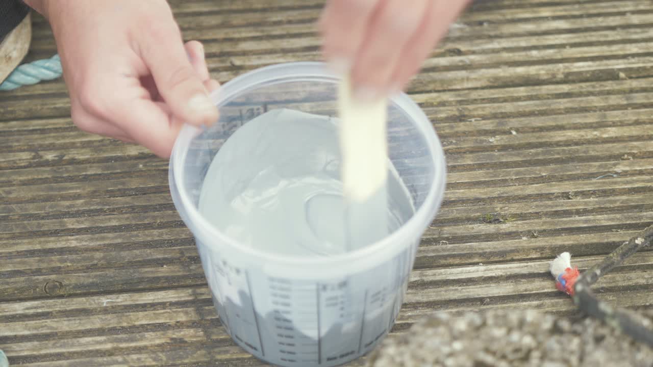 agitación de pintura gris en un recipiente de plástico