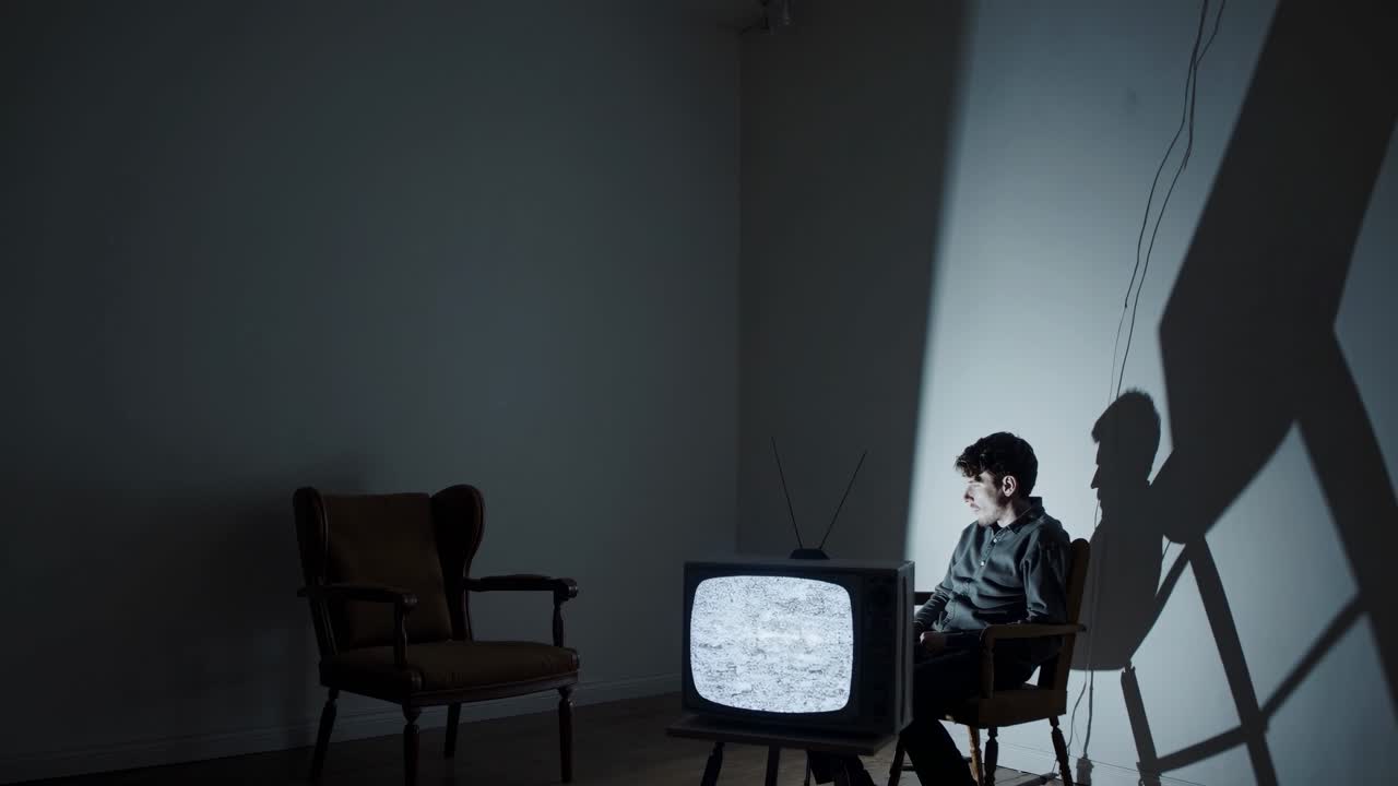 어두운 방에서 오래된 tv를 보는 남자