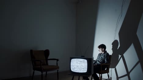hombre viendo una vieja televisión en una habitación oscura