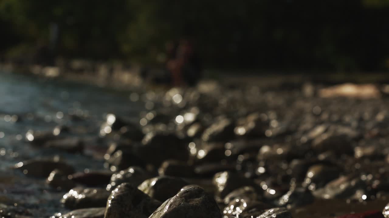 Rocce in primo piano a fuoco. Acqua che lambisce rocce sfocate.