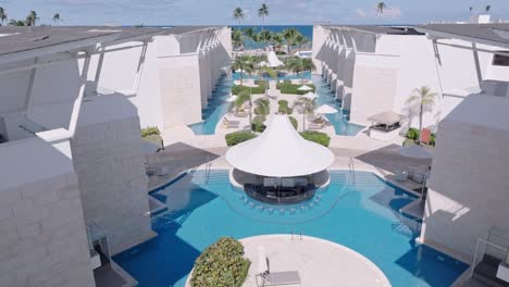 aerial forward over modern luxury pool area with loungers and palms, punta cana