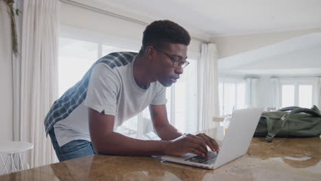 casually dressed man downloading data from personal health tracker to laptop at home