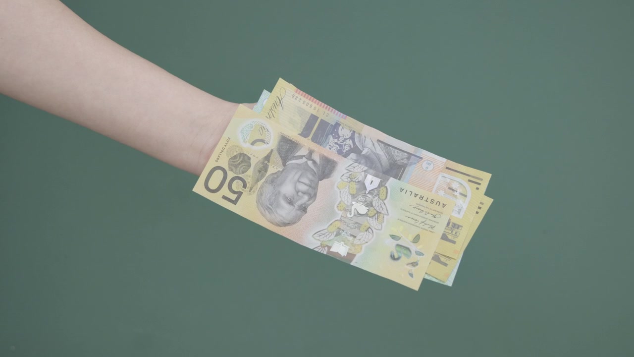 Une main d'homme paie une main de femme avec des billets de banque australiens qui s'accumulent en une grosse liasse d'argent, écran vert 4K
