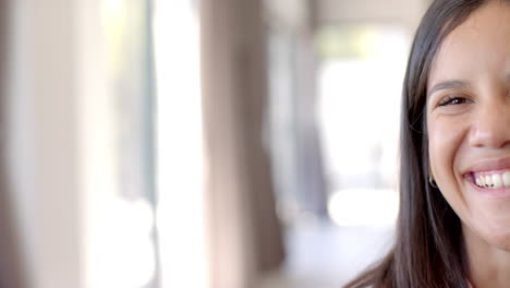 a young biracial female with long brown hair and brown eyes is smiling at home with copy space