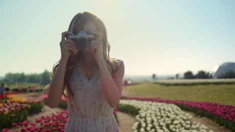 portrait beautiful lady with camera. happy woman walking in garden of flowers.