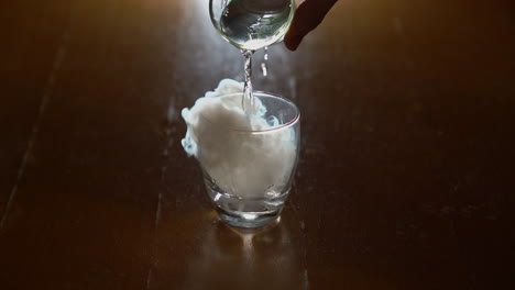 a man pours water over dry ice in a glass