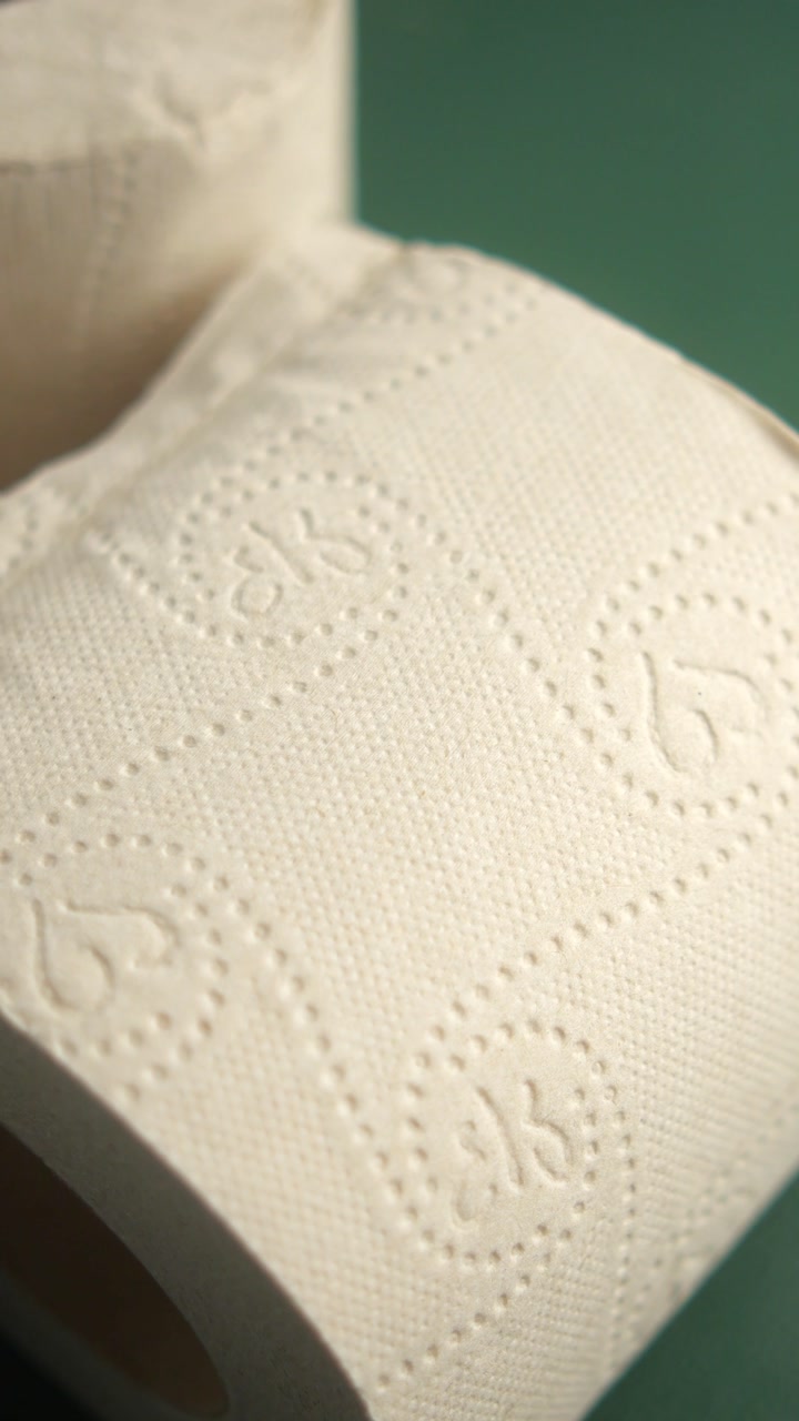 Close-up View of White Toilet Paper Rolls on Green Background