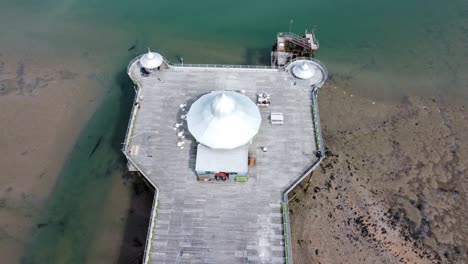 Bangor-seaside-pier-North-Wales-silver-spire-pavilion-low-tide-aerial-top-down-reverse-descend-view