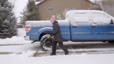 senior woman removing snow from her driveway with a shovel