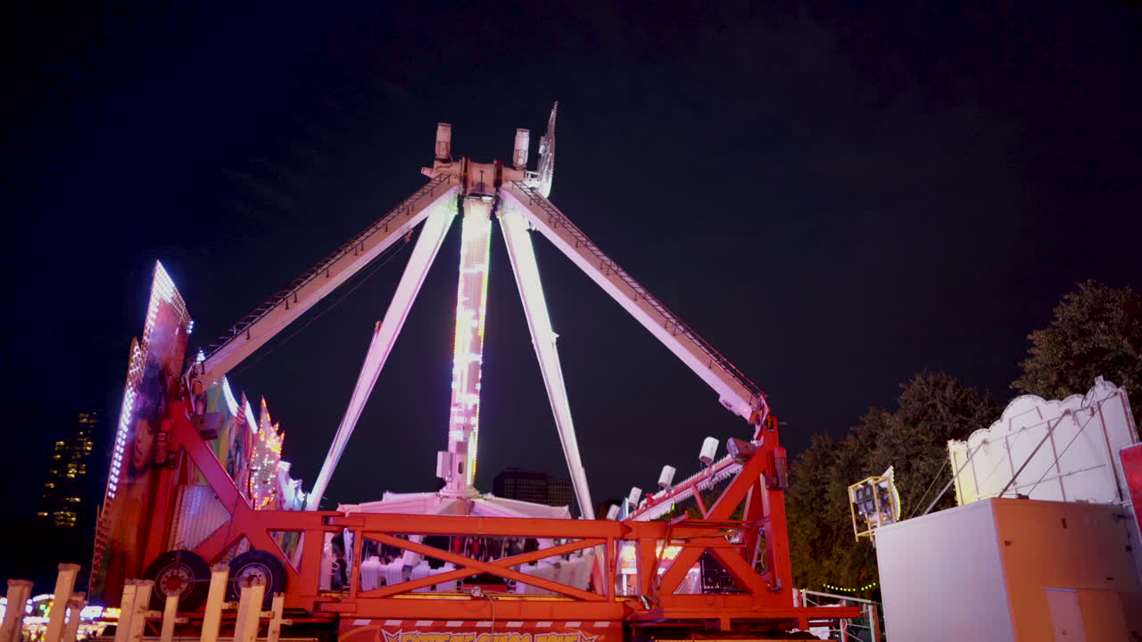 un columpio gigante va y viene en una feria por la noche