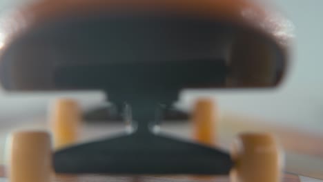 a hyper close-up macro detailed shot of a mini skateboard, tiny white wheels, riding fingerboard, finger sliding backwards in front of the camera, professional lighting, static cinematic 4k video