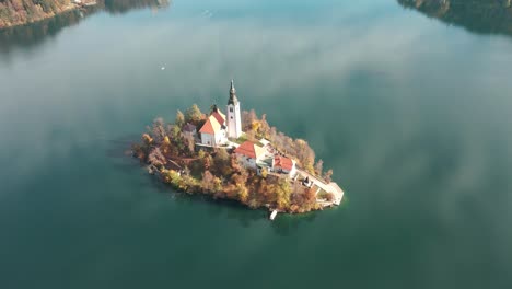 aerial view of lake bled island during the autumn season as the drone comes down to show more of bled in the background