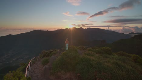 穿着运动服的适合徒步旅行的女人在山顶看着梦幻般的日出