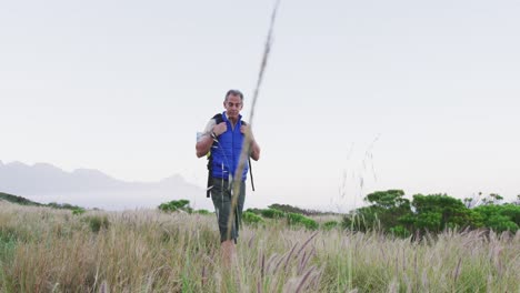 Älterer-Wanderer-Mit-Rucksack,-Der-Wildes-Gras-Auf-Der-Wiese-In-Den-Bergen-Spaziert-Und-Berührt.