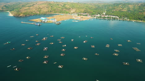 aerial view of many floating cages for fish and lobster farming at awang bay fishing harbour, lombok, mertak, indonesia